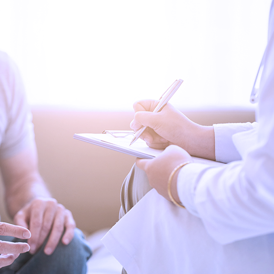 Arzt spricht mit Patient und macht sich Notizen